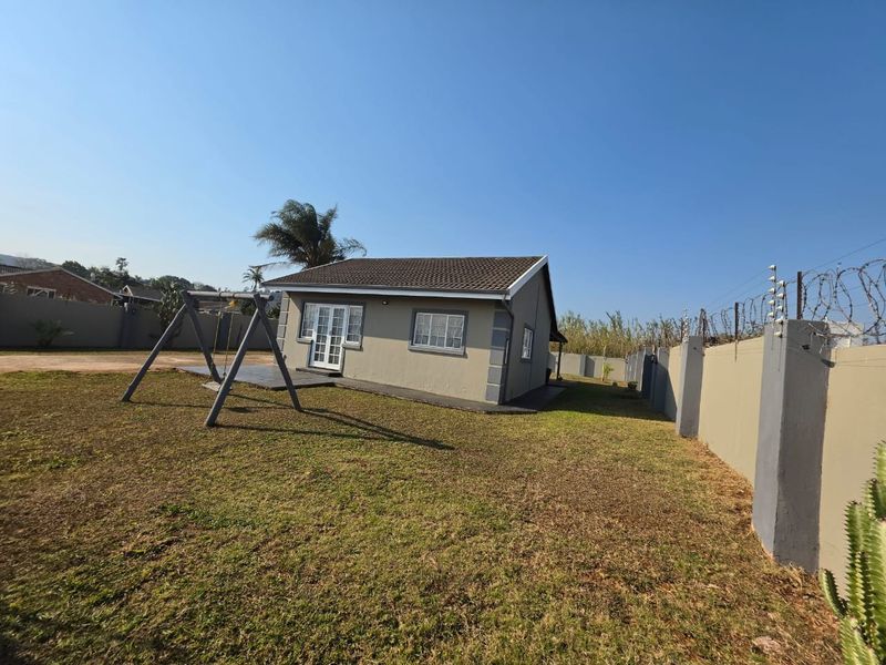 Rear view of the property featuring a tiled roof, french doors, paved patio area, and a secure perimeter wall with electric fencing.