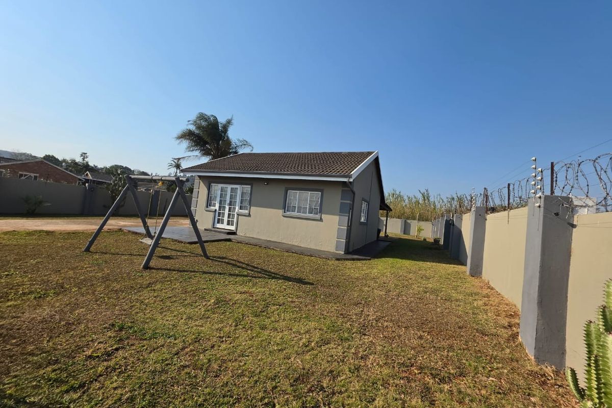 Rear view of the property featuring a tiled roof, french doors, paved patio area, and a secure perimeter wall with electric fencing.