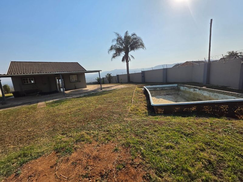 Outdoor area featuring a swimming pool, perimeter wall with security fencing, and a covered patio attached to the main house structure.