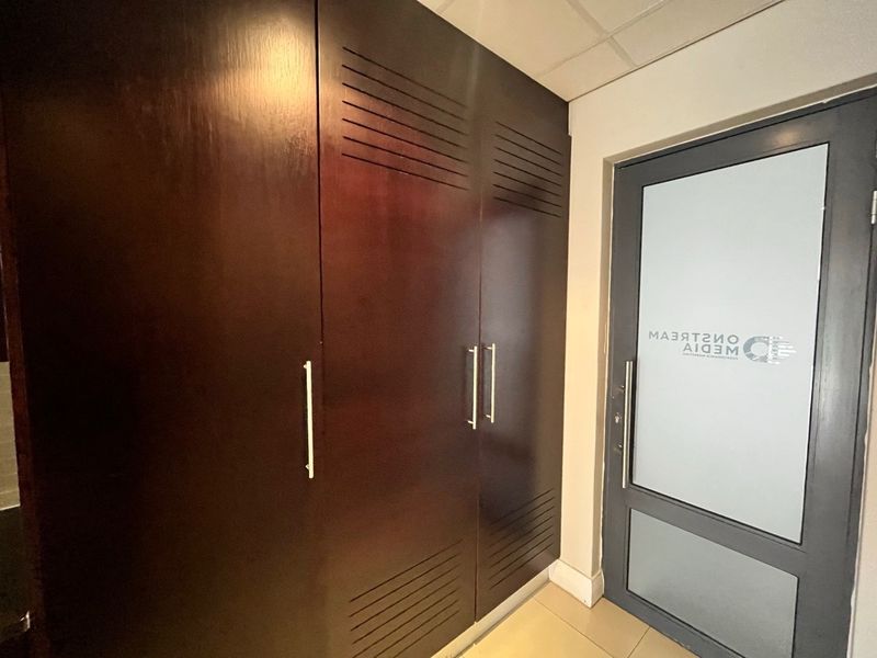 Office entrance area featuring dark wood built-in cabinetry and a modern frosted glass door with company branding.