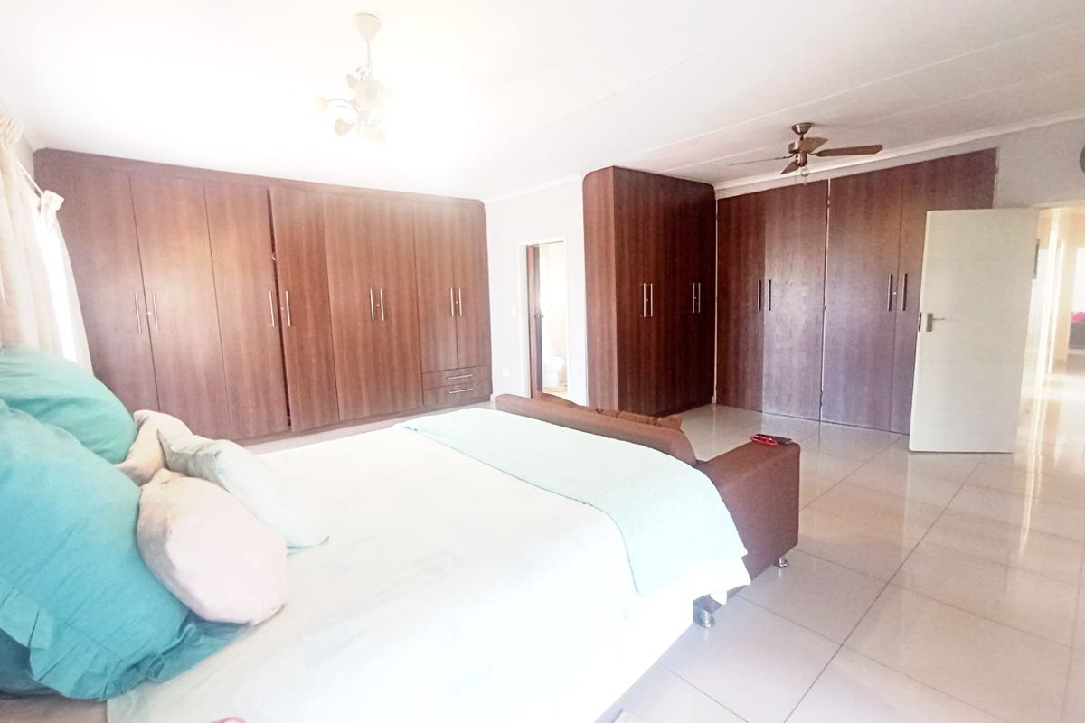 Spacious bedroom featuring extensive built-in wooden cabinetry, tiled flooring, and a ceiling fan, offering ample storage and a neutral foundation.