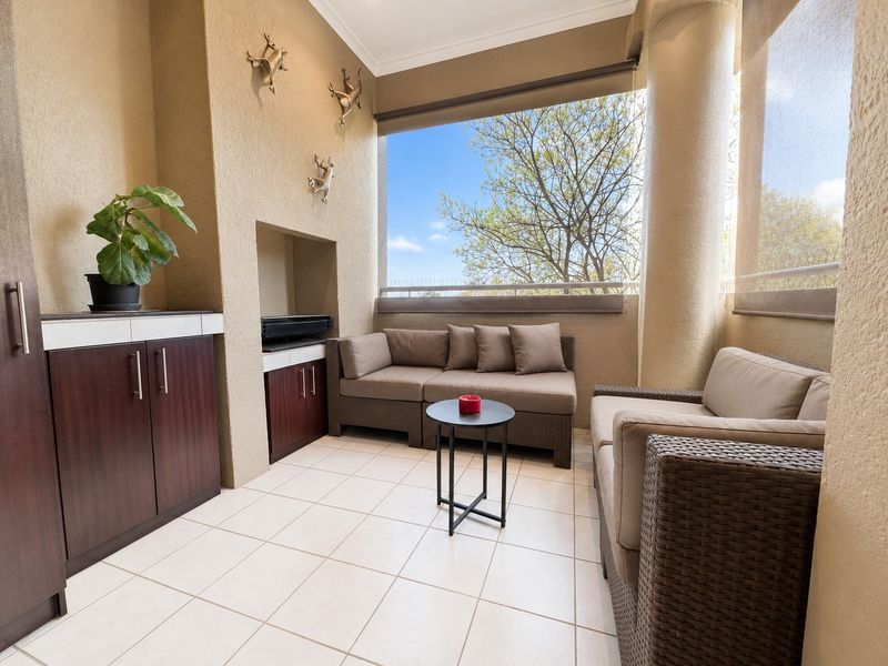 A covered balcony featuring tiled flooring, built-in cabinetry, and a recessed storage area, offering a comfortable outdoor living space.