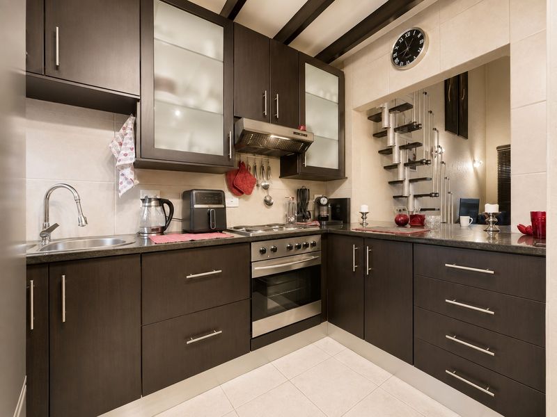 Modern kitchen featuring dark wood cabinetry, granite countertops, stainless steel appliances, and a tiled backsplash, offering a functional and stylish cooking space.