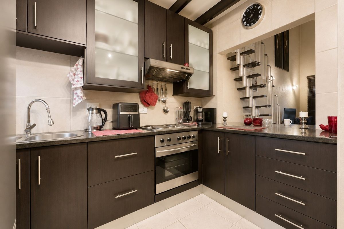 Modern kitchen featuring dark wood cabinetry, granite countertops, stainless steel appliances, and a tiled backsplash, offering a functional and stylish cooking space.