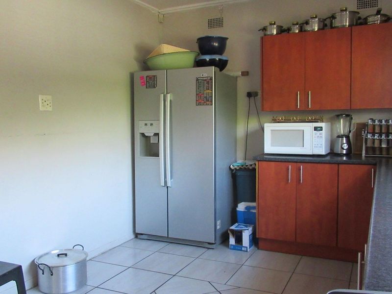 A functional kitchen featuring wood-look cabinetry, dark laminate countertops, and tiled flooring, providing a practical workspace for daily meal preparation.
