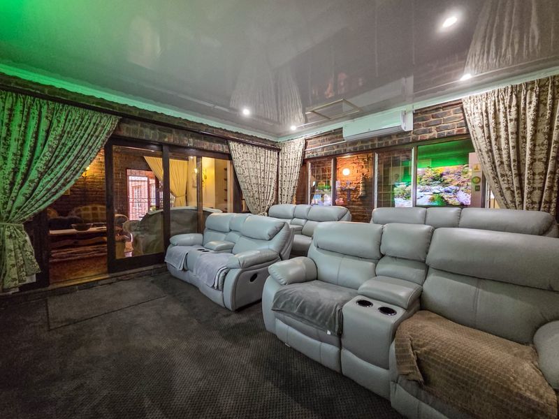 A dedicated cinema room featuring exposed brick walls, a high-gloss ceiling, and sliding glass doors leading to an adjacent space.