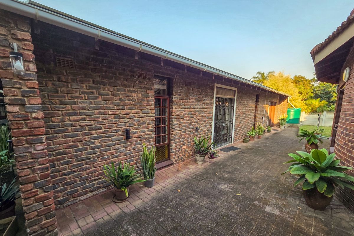 A well-maintained rear exterior view featuring face brick walls, a paved patio area, and secure access points.