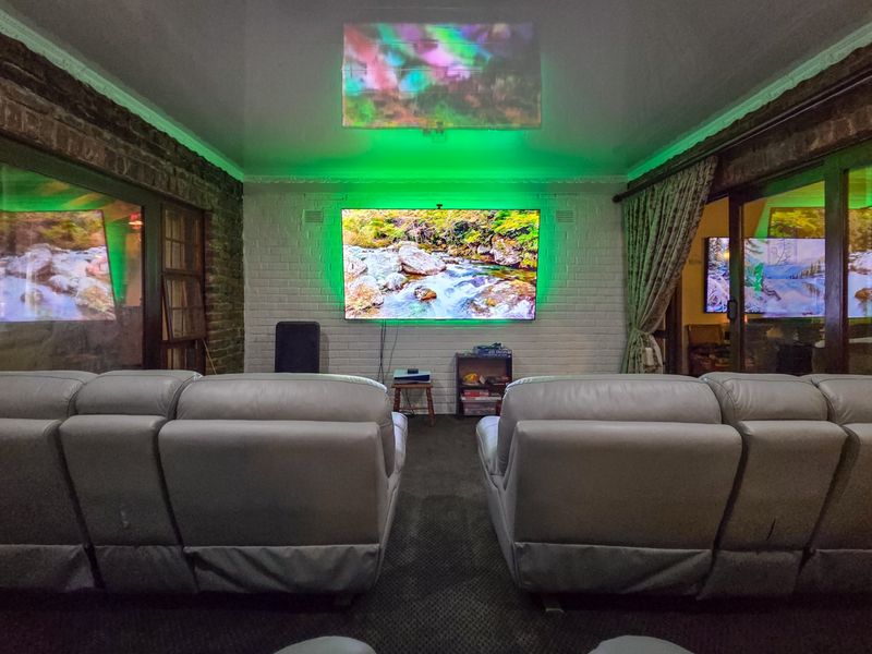 A dedicated cinema room featuring exposed and painted brick walls, integrated lighting, and sliding glass doors providing a cozy entertainment space.