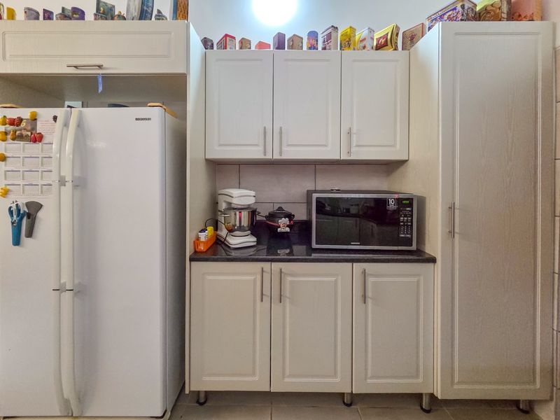 A functional kitchen area featuring light-toned built-in cabinetry, dark granite countertops, and a tiled backsplash, providing efficient storage and workspace.