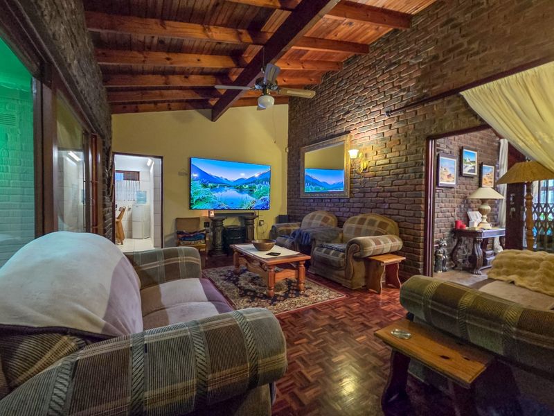 A rustic living room featuring exposed brick walls, a high timber beam ceiling, and classic parquet flooring, creating a warm and traditional atmosphere.