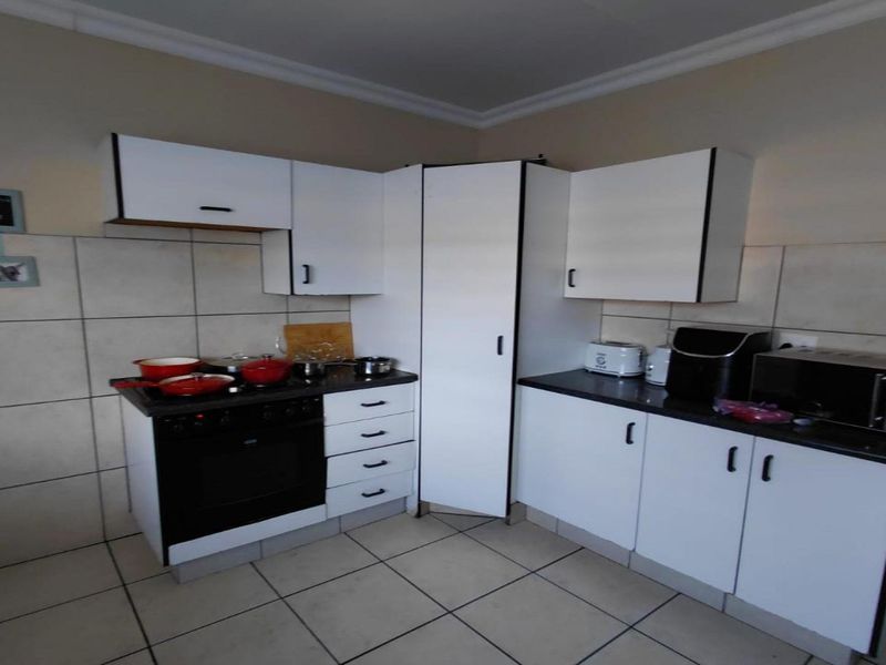 A functional kitchen featuring white built-in cabinetry, dark laminate countertops, a built-in oven and hob, and tiled flooring with a tiled splashback.