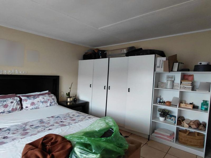 A bedroom featuring built-in cupboards and tiled flooring, providing functional storage space.