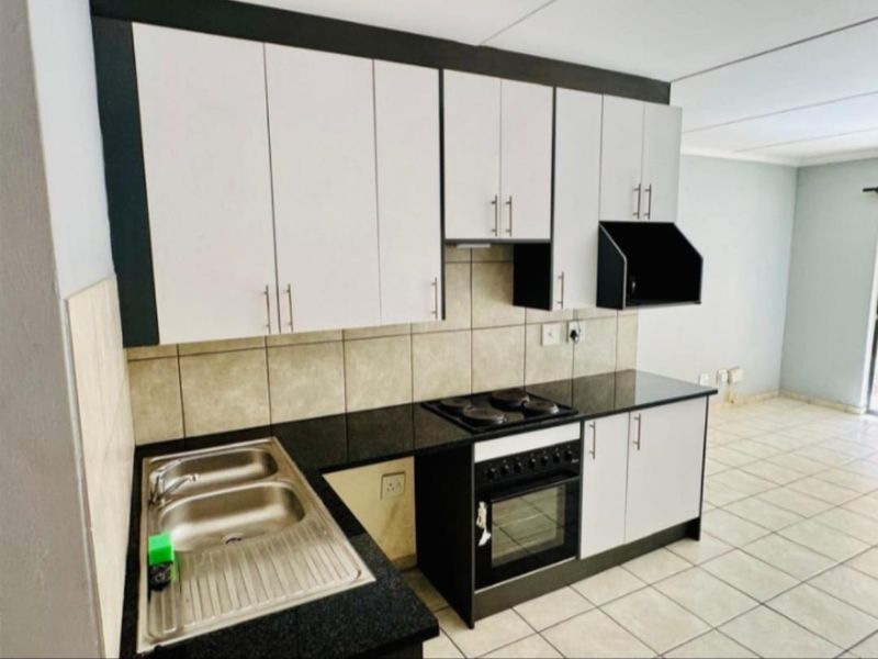 A functional kitchen featuring built-in cabinetry, granite countertops, a stainless steel sink, and an integrated electric stove and oven with a tiled backsplash.