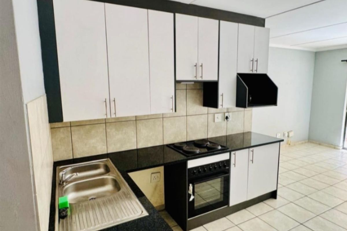 A functional kitchen featuring built-in cabinetry, granite countertops, a stainless steel sink, and an integrated electric stove and oven with a tiled backsplash.