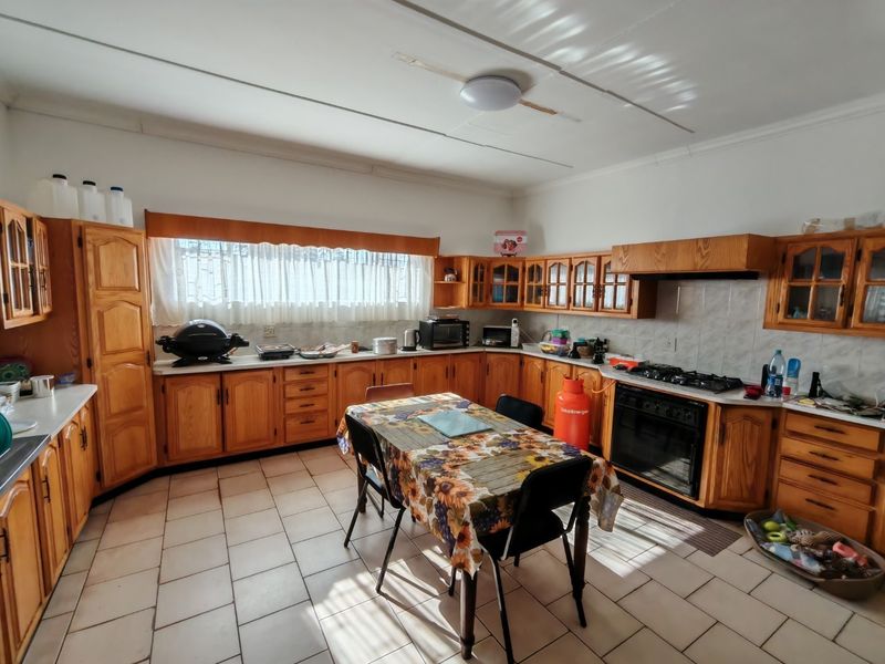 Spacious kitchen featuring traditional wooden cabinetry, tiled flooring, and a built-in gas hob and oven, offering a functional layout with ample storage space.