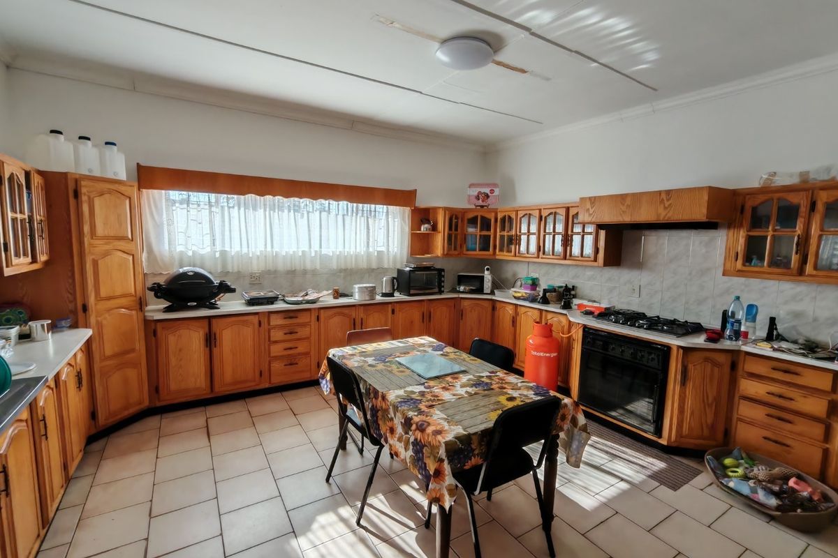 Spacious kitchen featuring traditional wooden cabinetry, tiled flooring, and a built-in gas hob and oven, offering a functional layout with ample storage space.