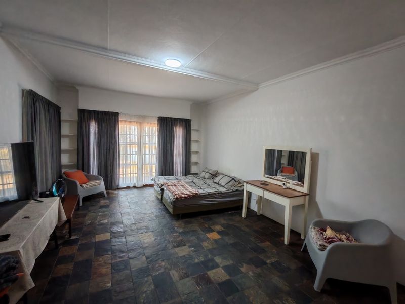 Spacious bedroom featuring dark slate tile flooring, built-in shelving units, and a sliding glass door providing natural light and access to the exterior.