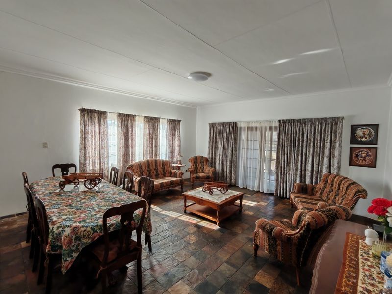 Spacious open-plan living and dining area featuring traditional slate tile flooring and large sliding glass doors providing ample natural light.