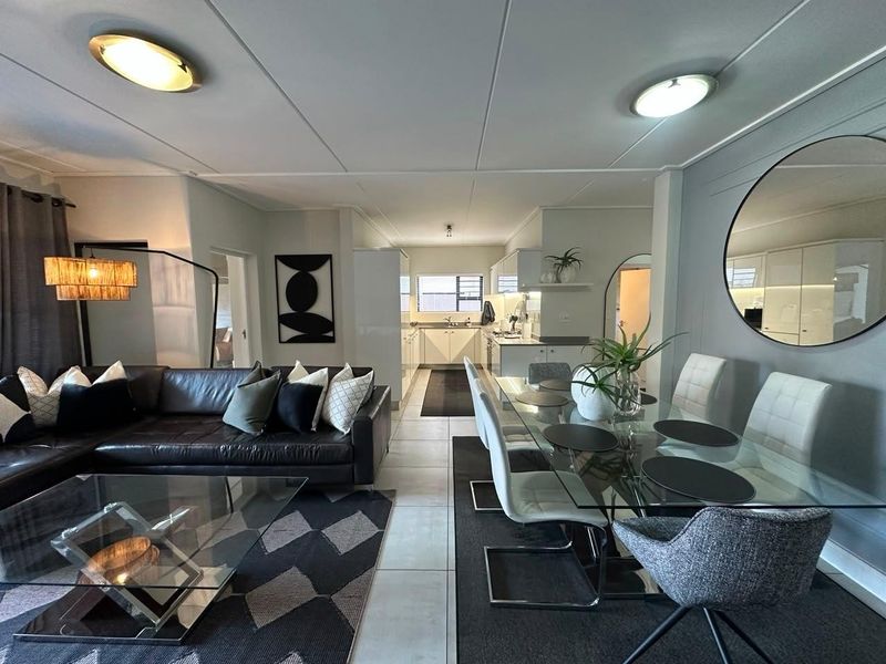 Spacious open-plan living and dining area flowing into a modern kitchen with clean lines, neutral finishes, and bright, functional lighting throughout.