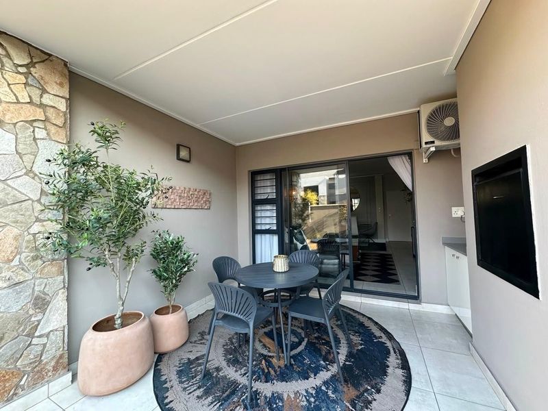 A covered patio featuring stone cladding, tiled flooring, and a built-in cabinet, providing a seamless transition to the interior living space.