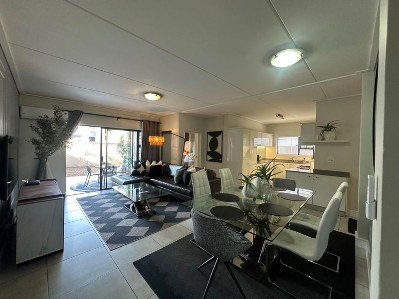 Open-plan living and dining area featuring tiled floors, a split-system air conditioner, and direct access to an outdoor patio through sliding glass doors.