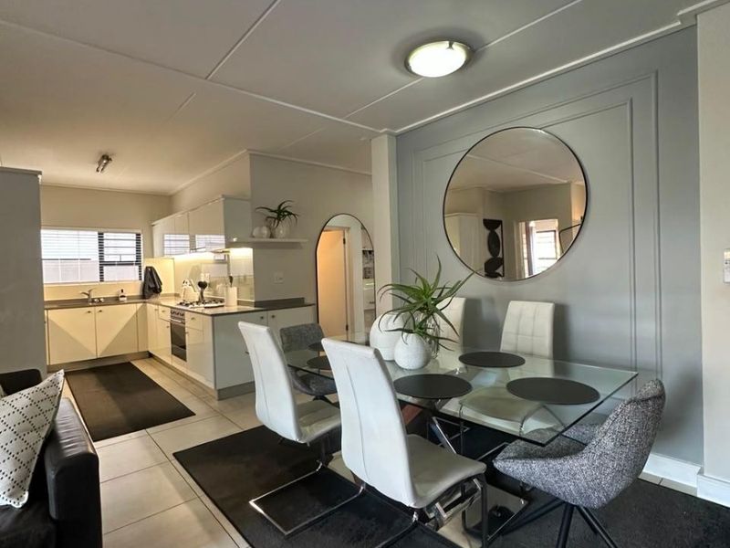 Open-plan living and dining area featuring a modern kitchen with built-in cabinetry, integrated appliances, and elegant wall molding details.