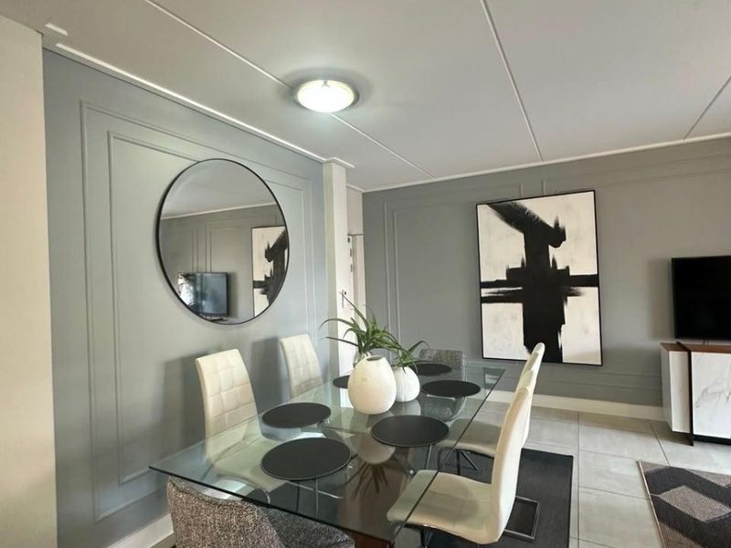 A well-maintained dining area featuring decorative wall paneling, neutral grey tones, and modern tiled flooring, creating a sophisticated and cohesive living space.