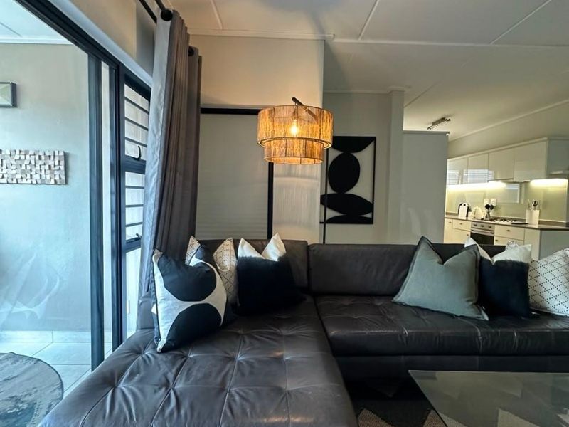Open plan living area featuring tiled floors, a sliding door to the patio, and a modern kitchen with built-in appliances.