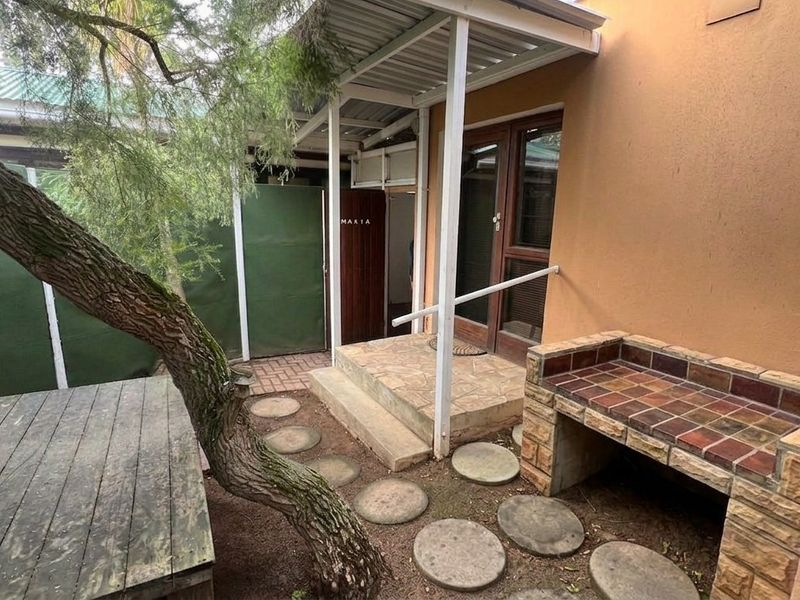A covered outdoor patio area featuring a built-in braai, paved flooring, and direct access to the home.
