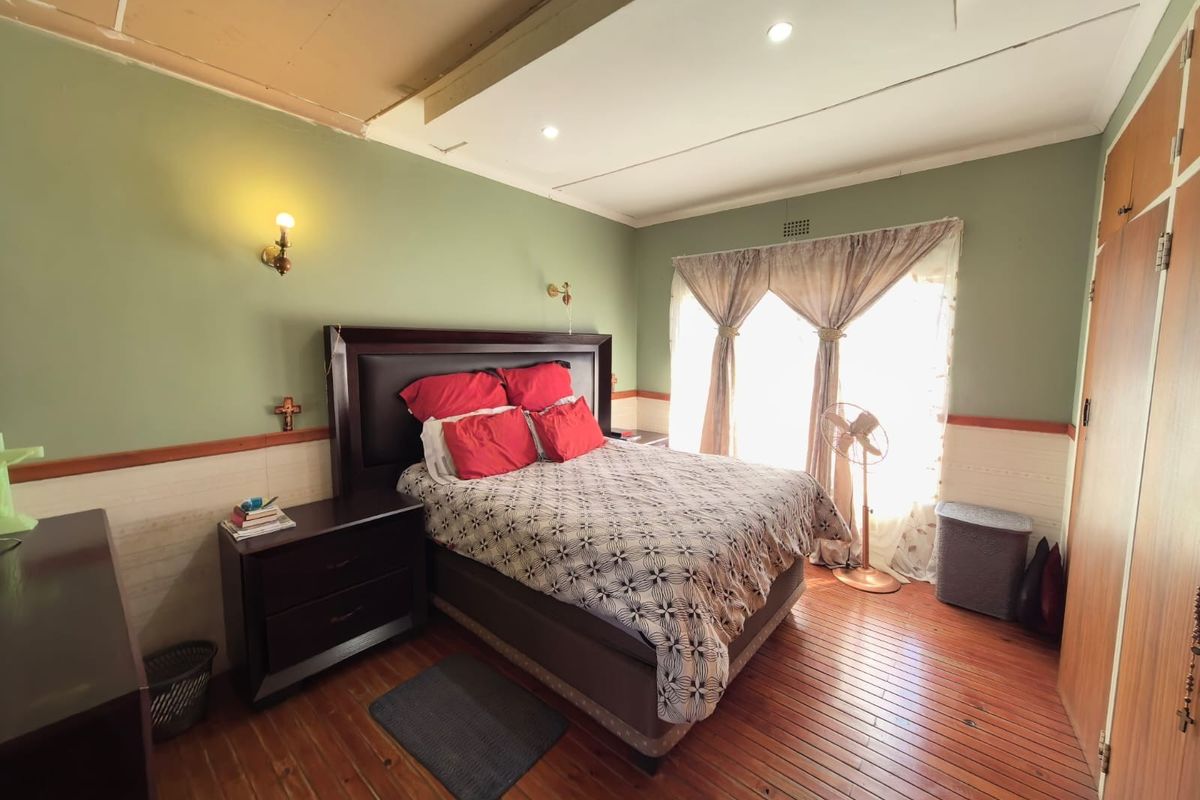A bedroom featuring hardwood flooring, built-in cupboards, and wall-mounted lighting, currently requiring ceiling repairs and cosmetic updates.