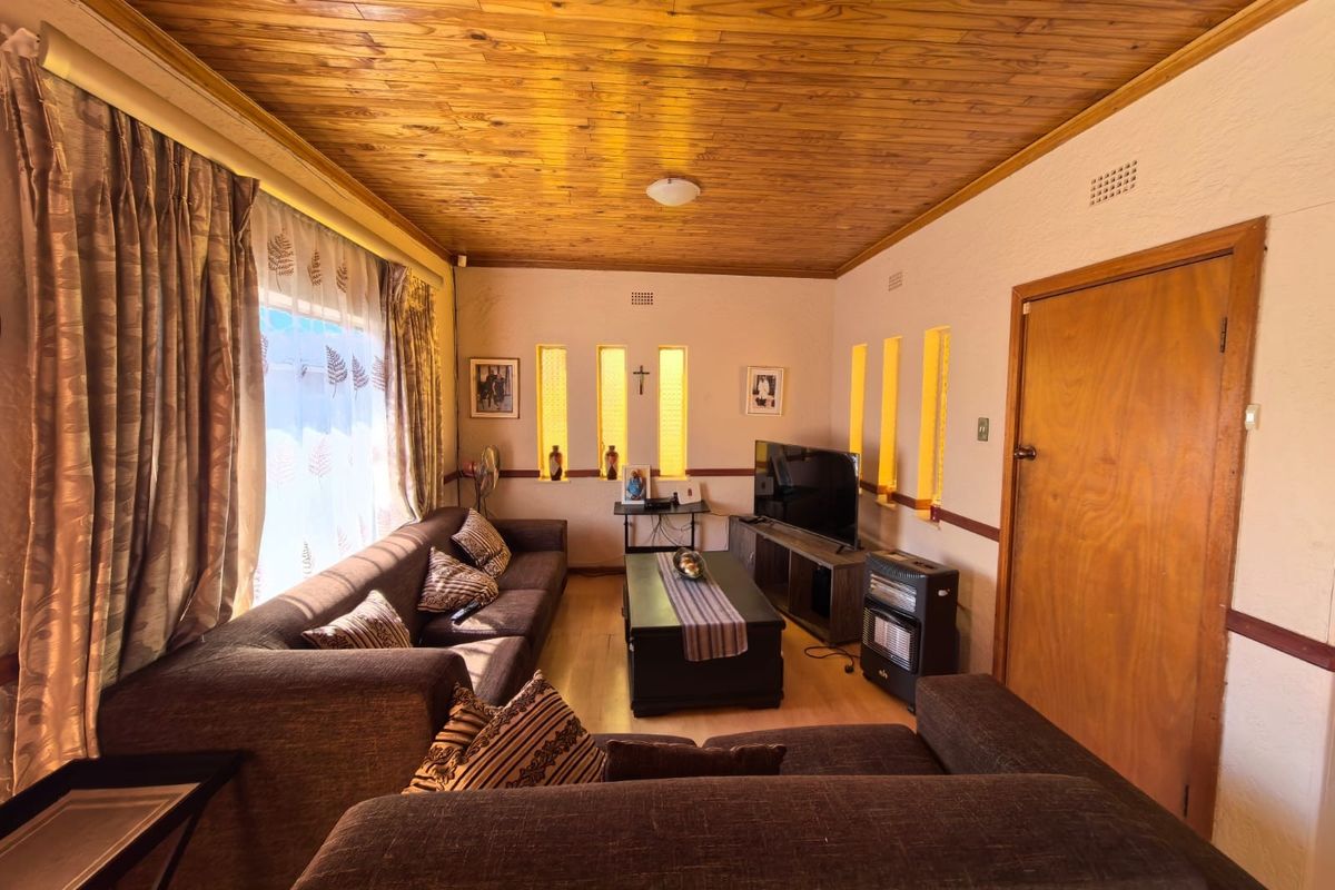 A living room featuring a timber-clad ceiling, laminate flooring, and unique vertical feature windows, providing a warm and traditional aesthetic.