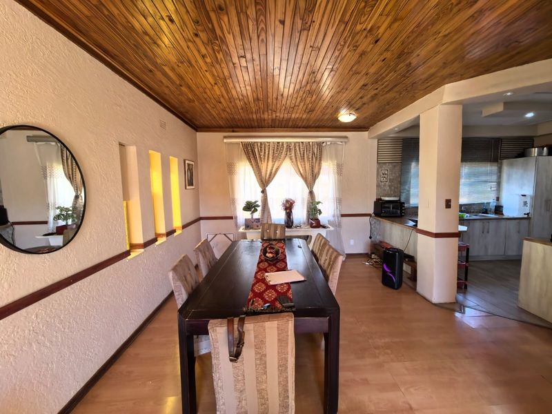 Open plan dining area featuring a timber ceiling and recessed wall niches, flowing into a functional kitchen space with built-in cabinetry.