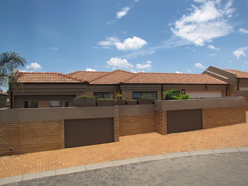 Front exterior view of a single-story brick house featuring a tiled roof, paved driveway, and a secure boundary wall.