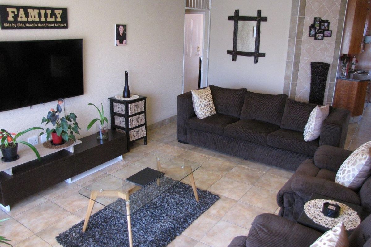 A living room featuring tiled flooring and a tiled fireplace surround, providing a functional and neutral space for relaxation.