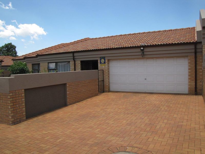 Front exterior view of the property featuring a paved driveway, a single sectional garage door, and a brick boundary wall.