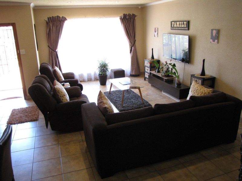 A comfortable living room featuring tiled flooring, recessed lighting, and a large window that provides ample natural light.