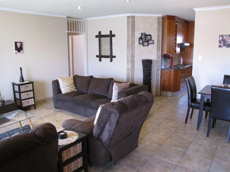 Open-plan living and dining area featuring tiled flooring, recessed lighting, and an adjoining kitchen with built-in cabinetry and stone countertops.