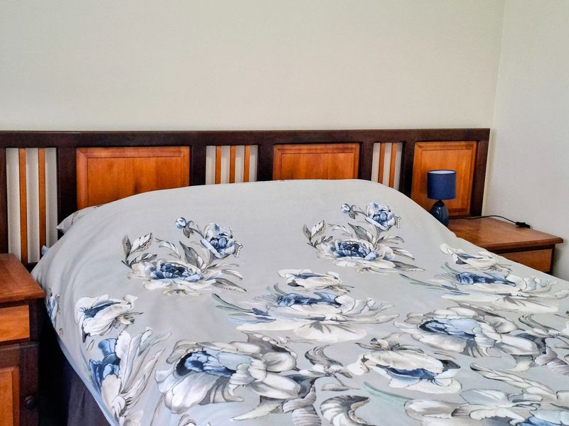 A bedroom featuring a built-in wooden headboard with integrated side tables.