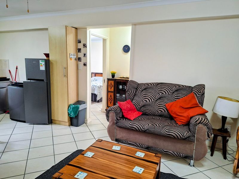 Open plan living area featuring tiled flooring and a built-in storage cupboard, with direct access to an adjacent bedroom.