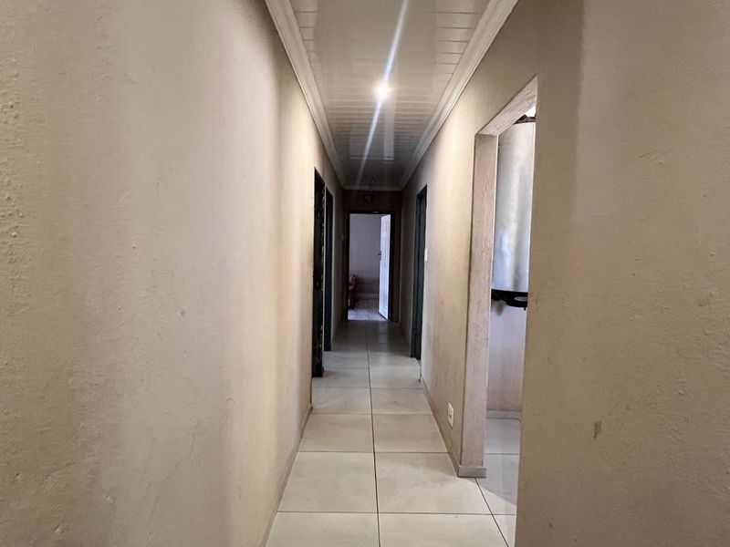 A functional hallway featuring tiled flooring and a panelled ceiling, providing access to multiple rooms within the home.