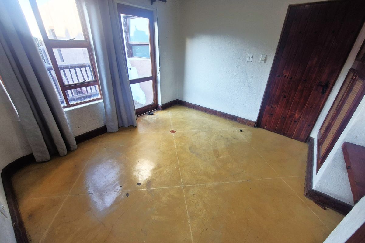 An empty bedroom featuring polished concrete flooring, timber door, and access to a balcony through aluminium framed doors.