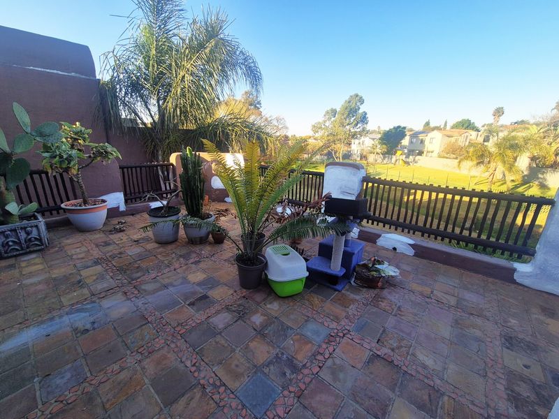 An open-air balcony featuring stone tile flooring and a timber balustrade, offering an elevated view of the surrounding neighborhood.