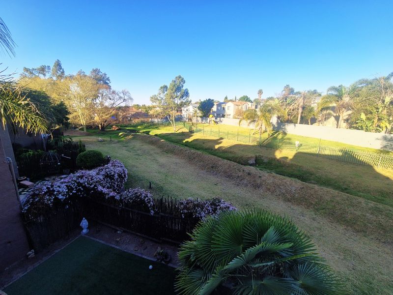 Elevated view overlooking a landscaped communal garden area with perimeter fencing and mature trees in a residential setting.
