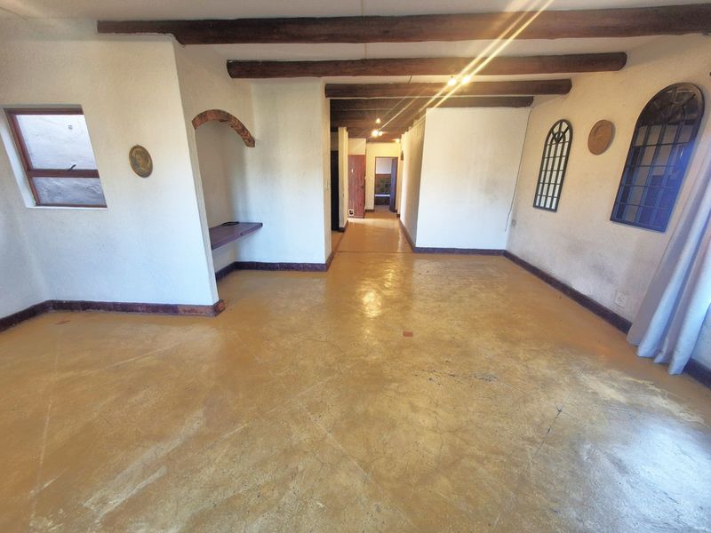 Spacious living area featuring exposed timber ceiling beams, polished concrete flooring, and unique arched architectural details throughout the room.
