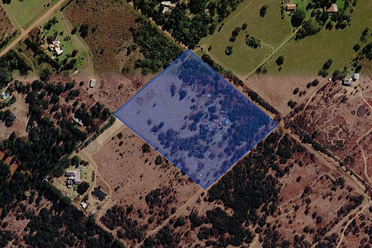 Aerial view of a large rural farm property with defined boundaries, showcasing the expansive land and existing structures.
