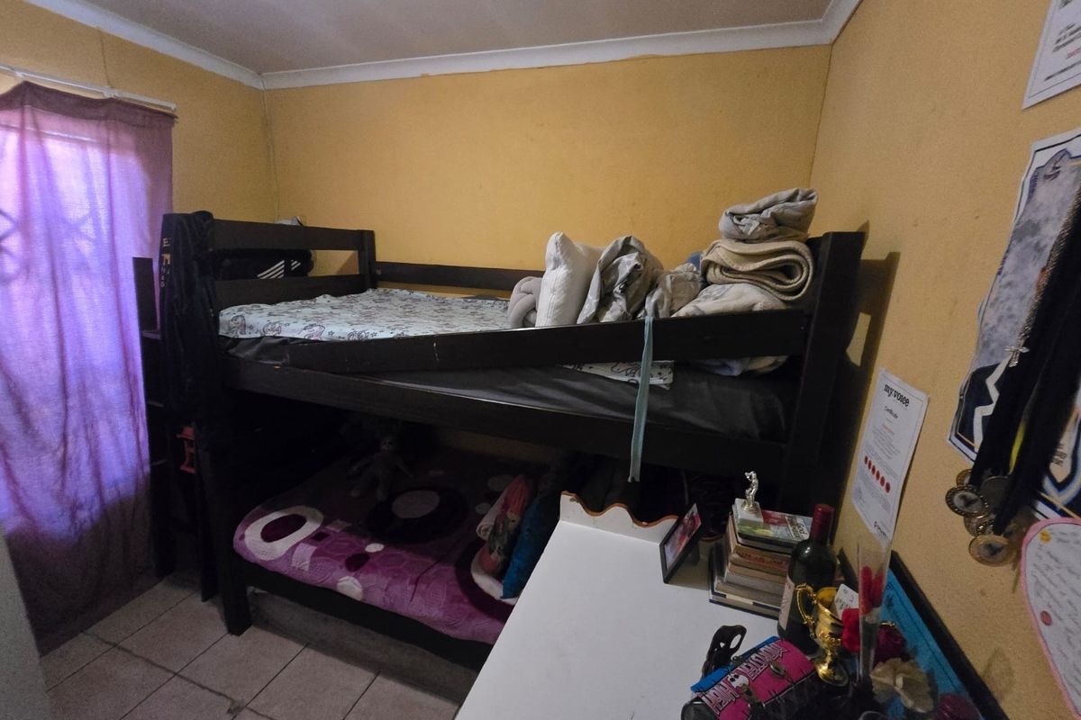 A compact bedroom featuring tiled flooring and coved ceilings, currently utilized with bunk bed furniture.