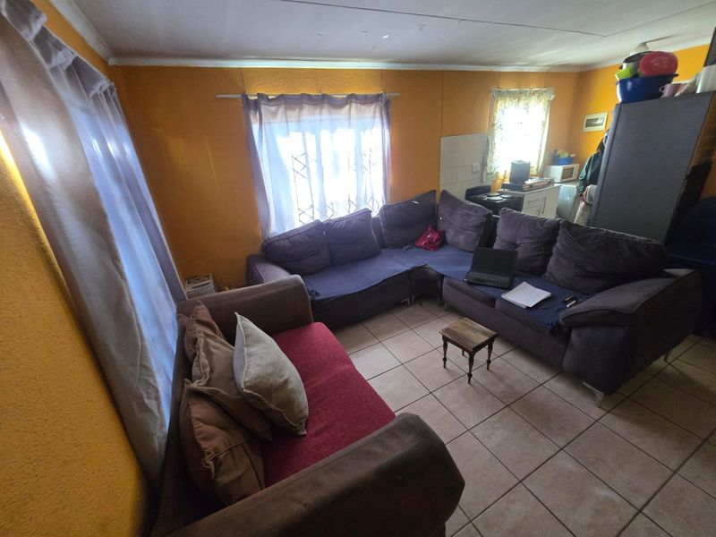 Open plan living area featuring tiled flooring and integrated kitchen space, requiring cosmetic updates to improve the overall aesthetic and condition.