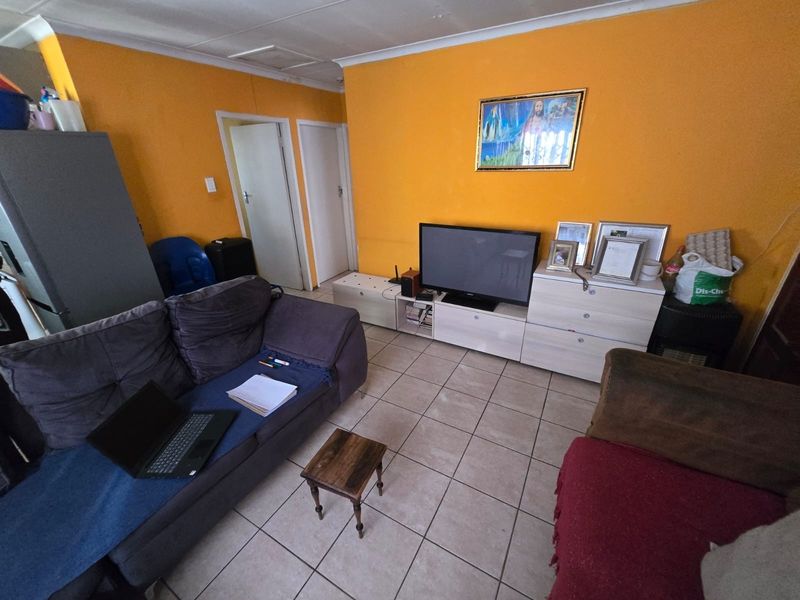 A living room featuring tiled flooring and bright orange walls, offering a functional space that could benefit from cosmetic updates and modern finishes.