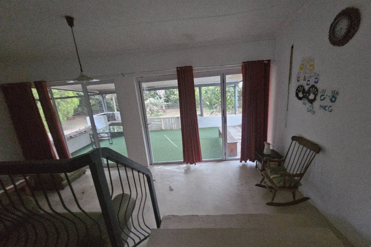 Living area featuring large sliding glass doors leading to an outdoor patio, with a metal staircase and neutral flooring.