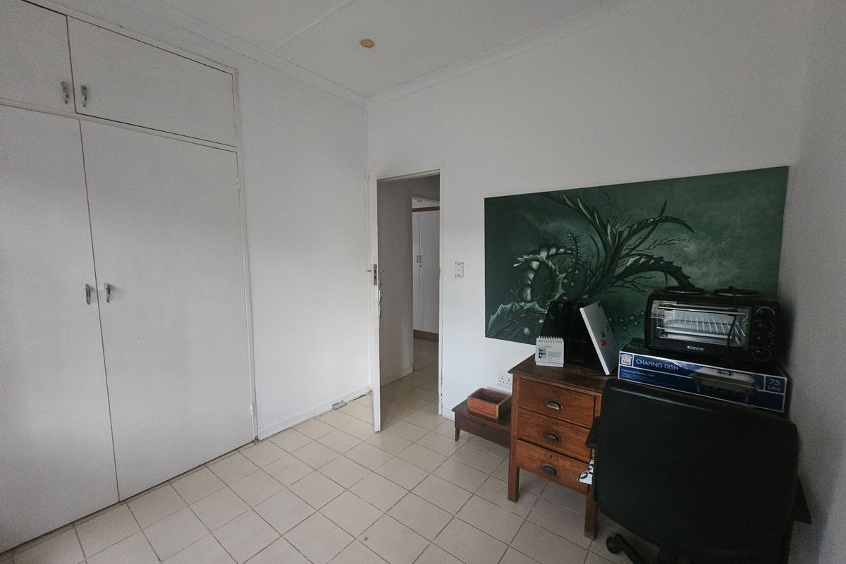 A bedroom featuring built-in cupboards and tiled flooring, offering a functional space with potential for cosmetic updates.